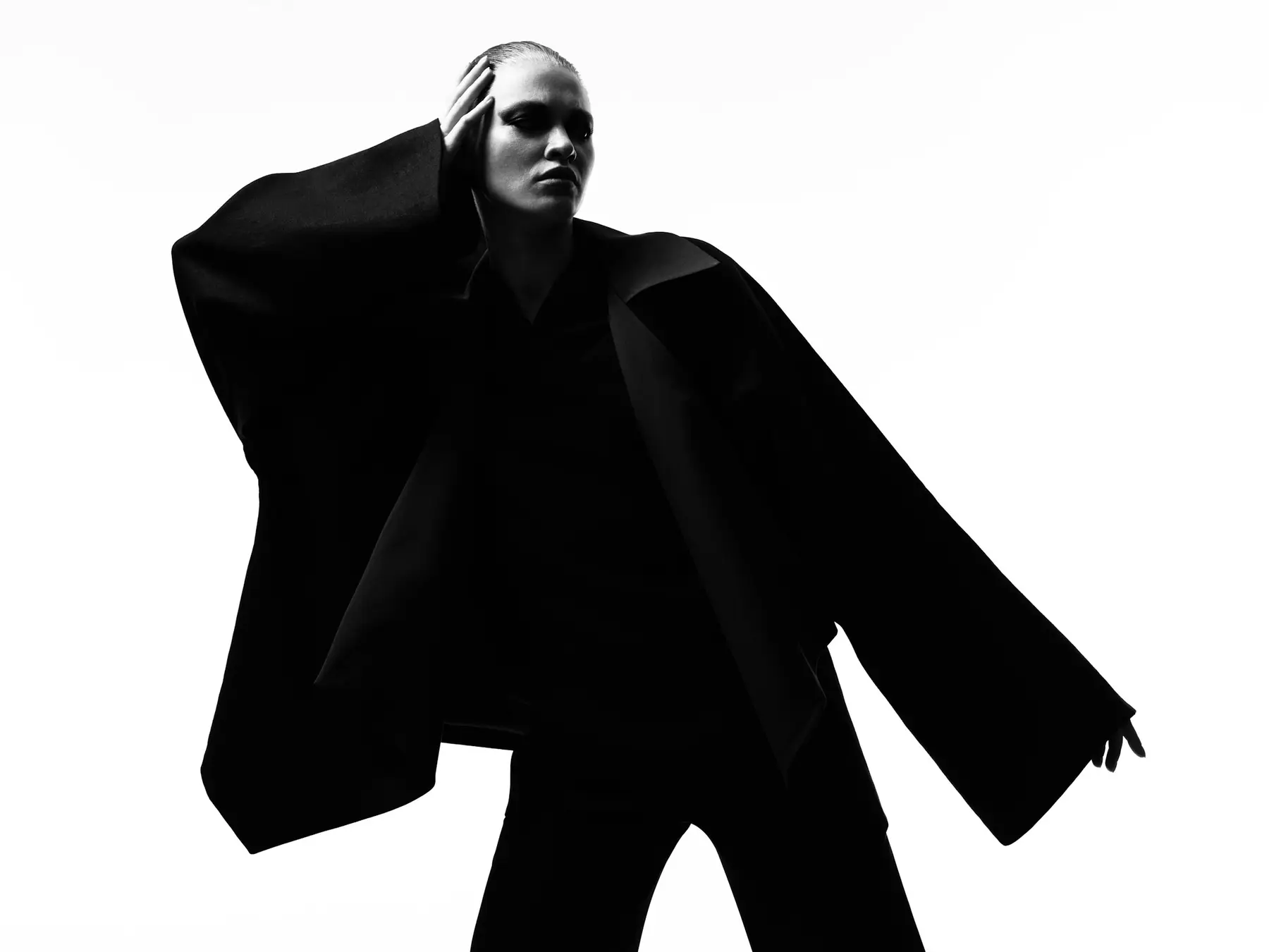 A wide black cape coat held open like wings against a white ground