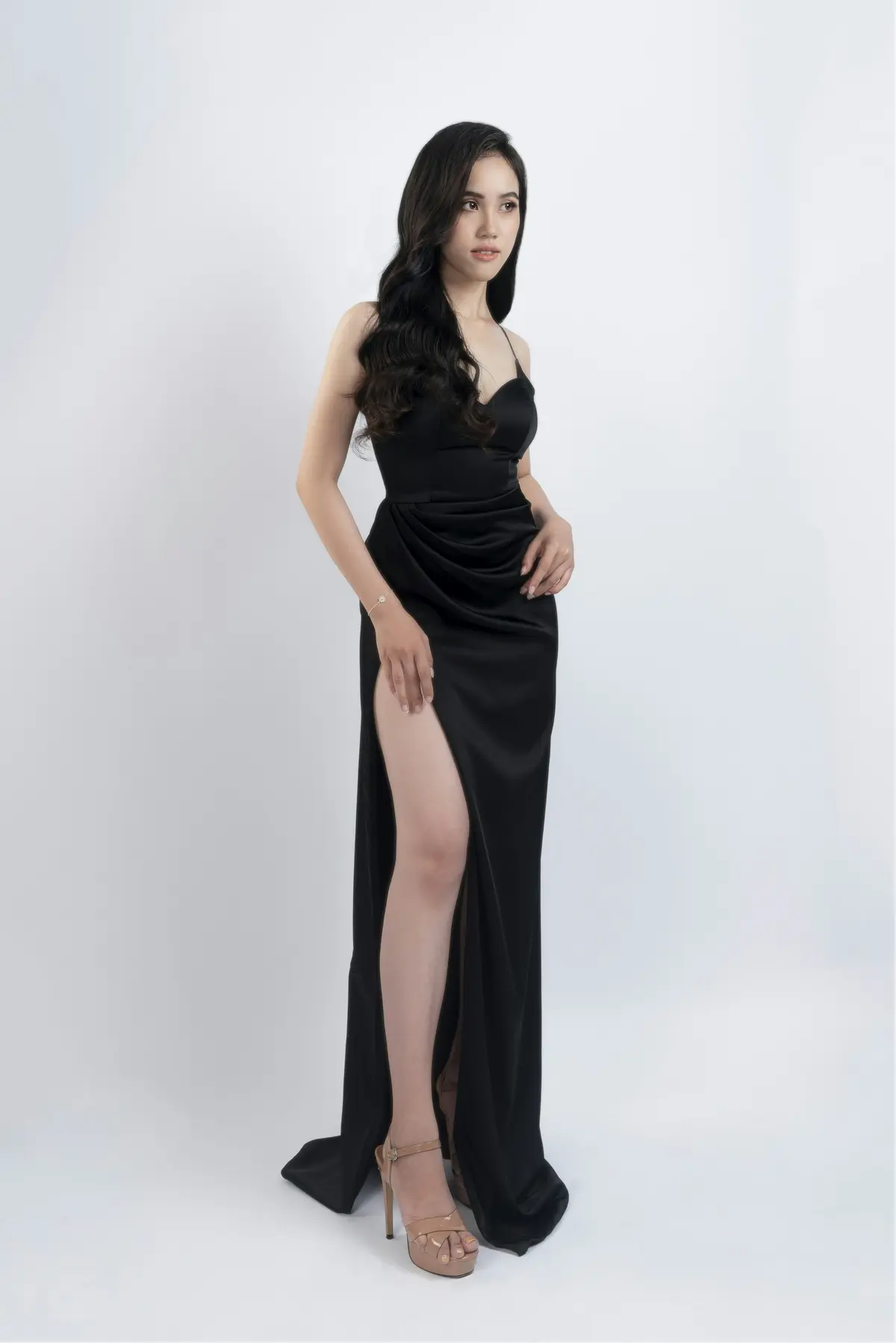 A floor-length black bias-cut slip gown with a high leg split
