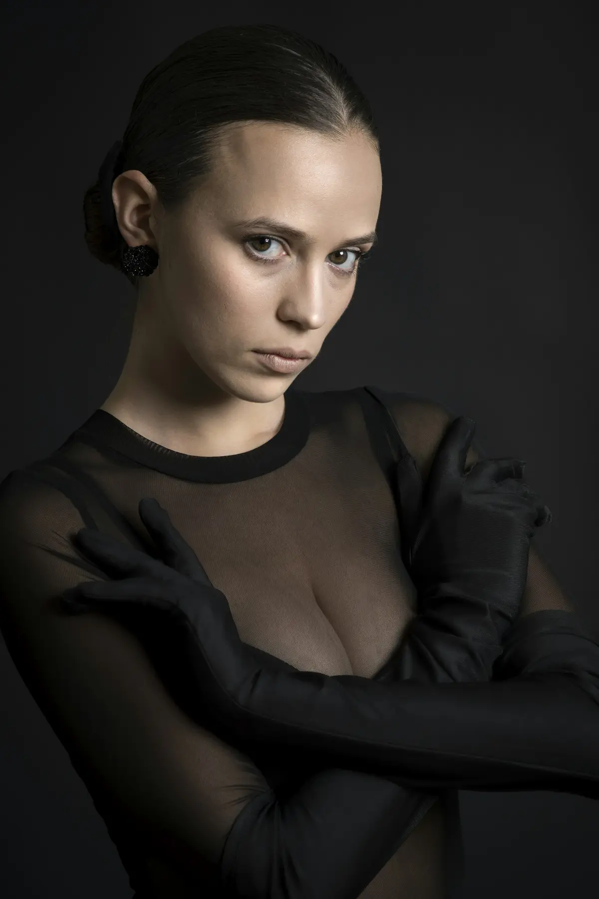 A sheer black tulle bodysuit with a high round neck, worn with long gloves