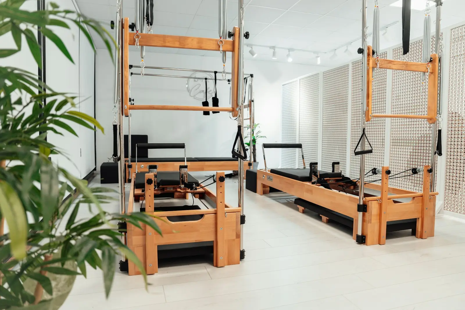 The reformer room: birch reformers and towers in a white room with plants.