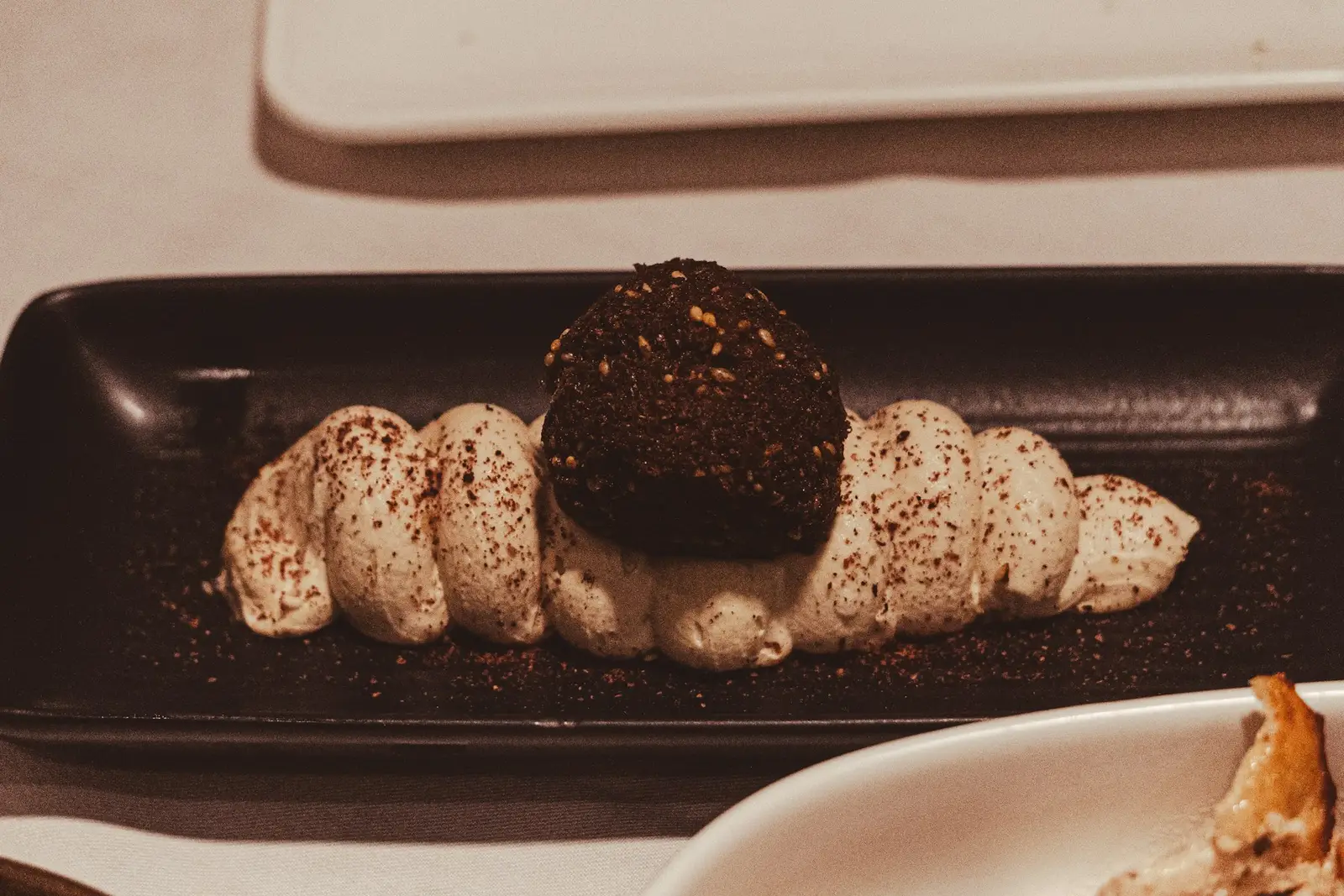 A dark chocolate dessert with cream on a black plate