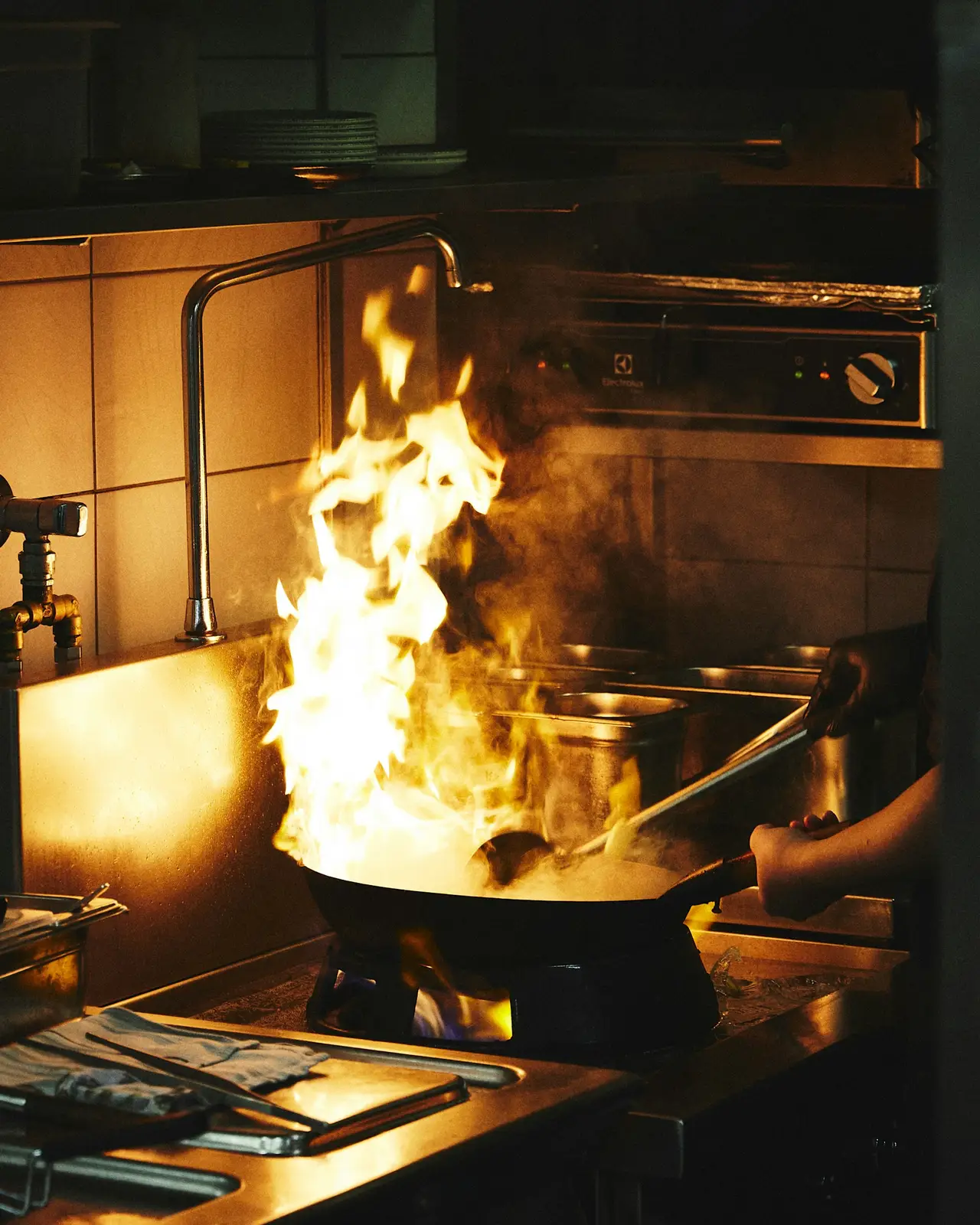 Flames leaping from a pan on a busy kitchen line