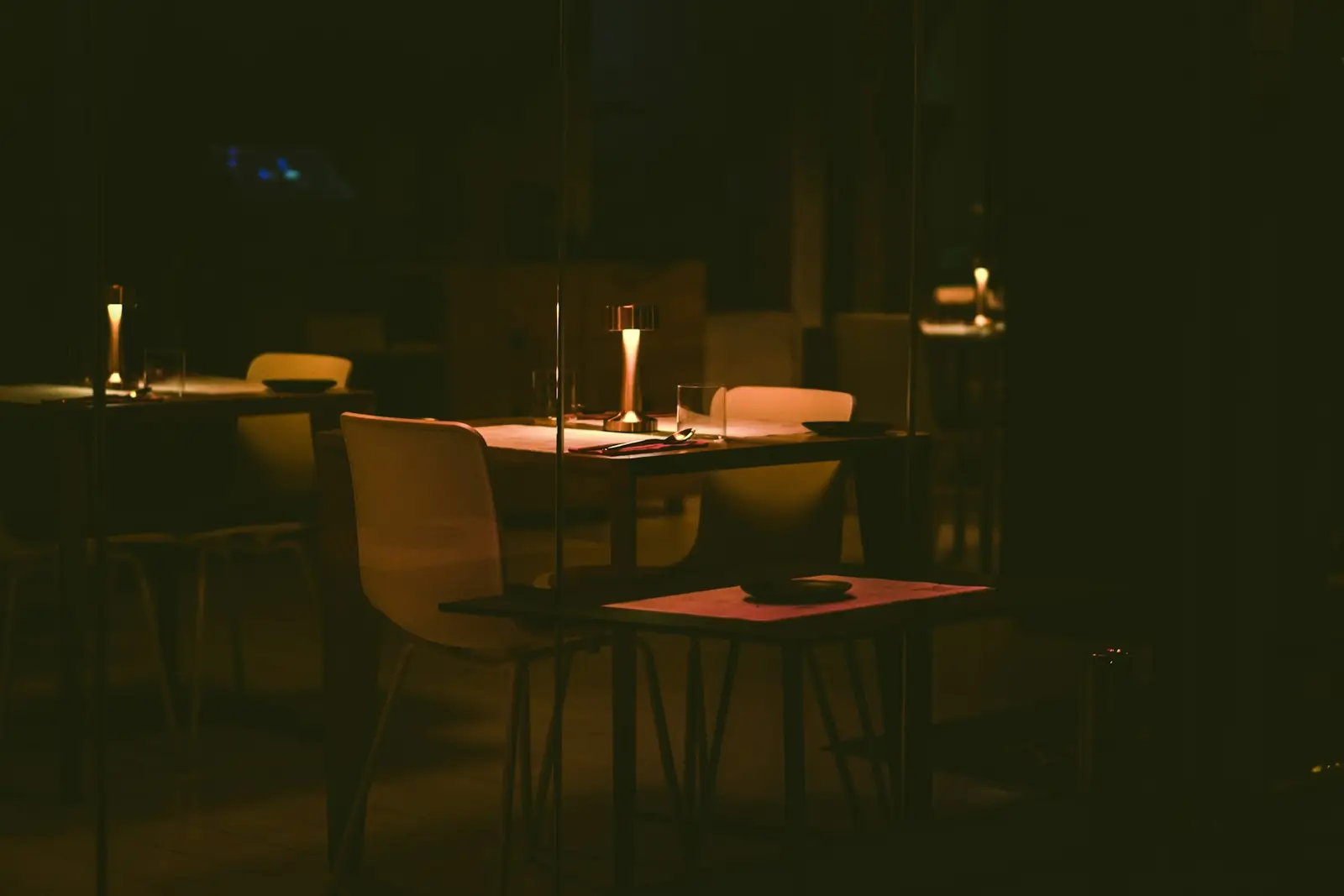 A dim dining room with set tables and candles