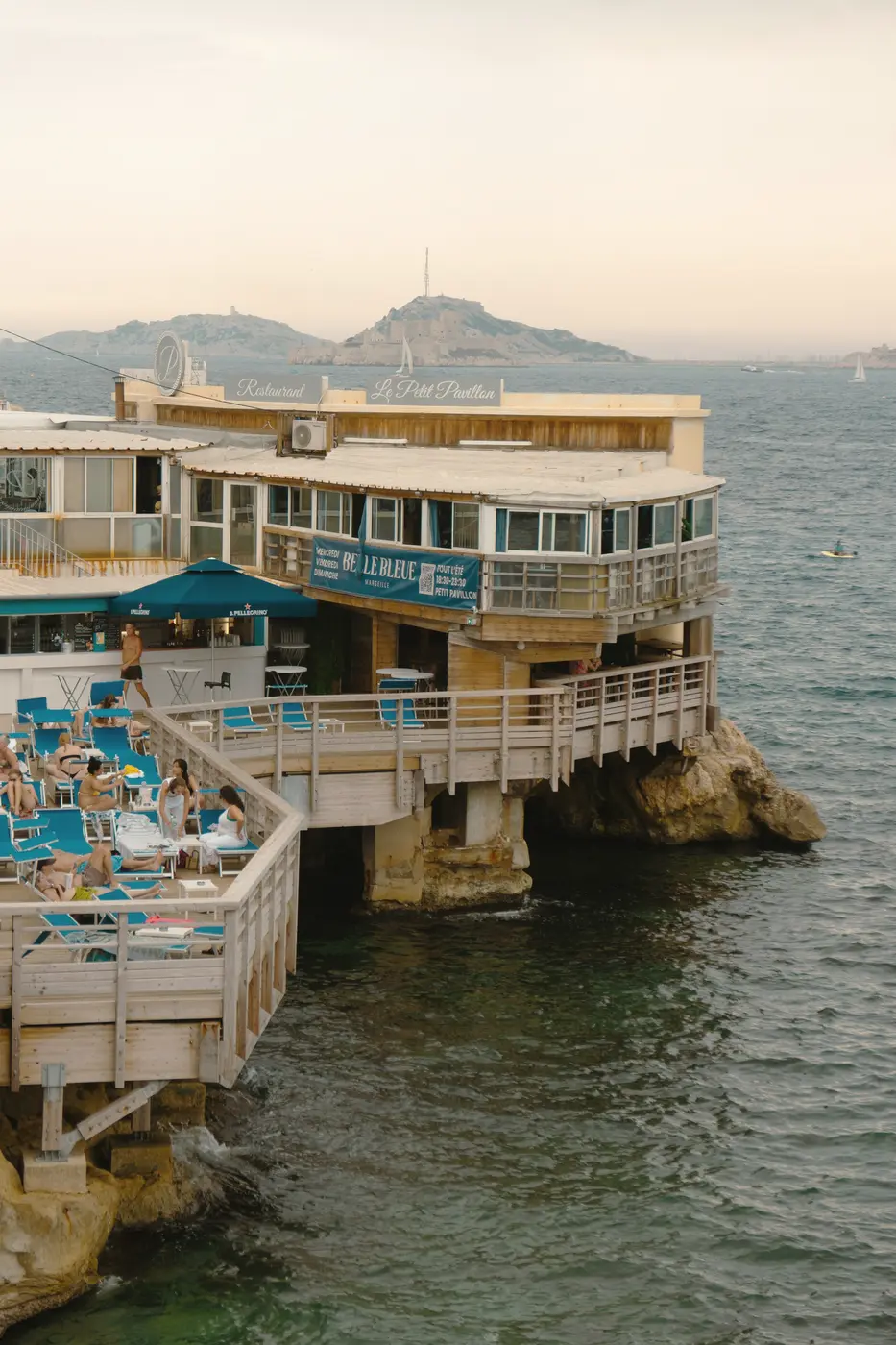 A seaside lido with blue umbrellas on terraces built over the rocks