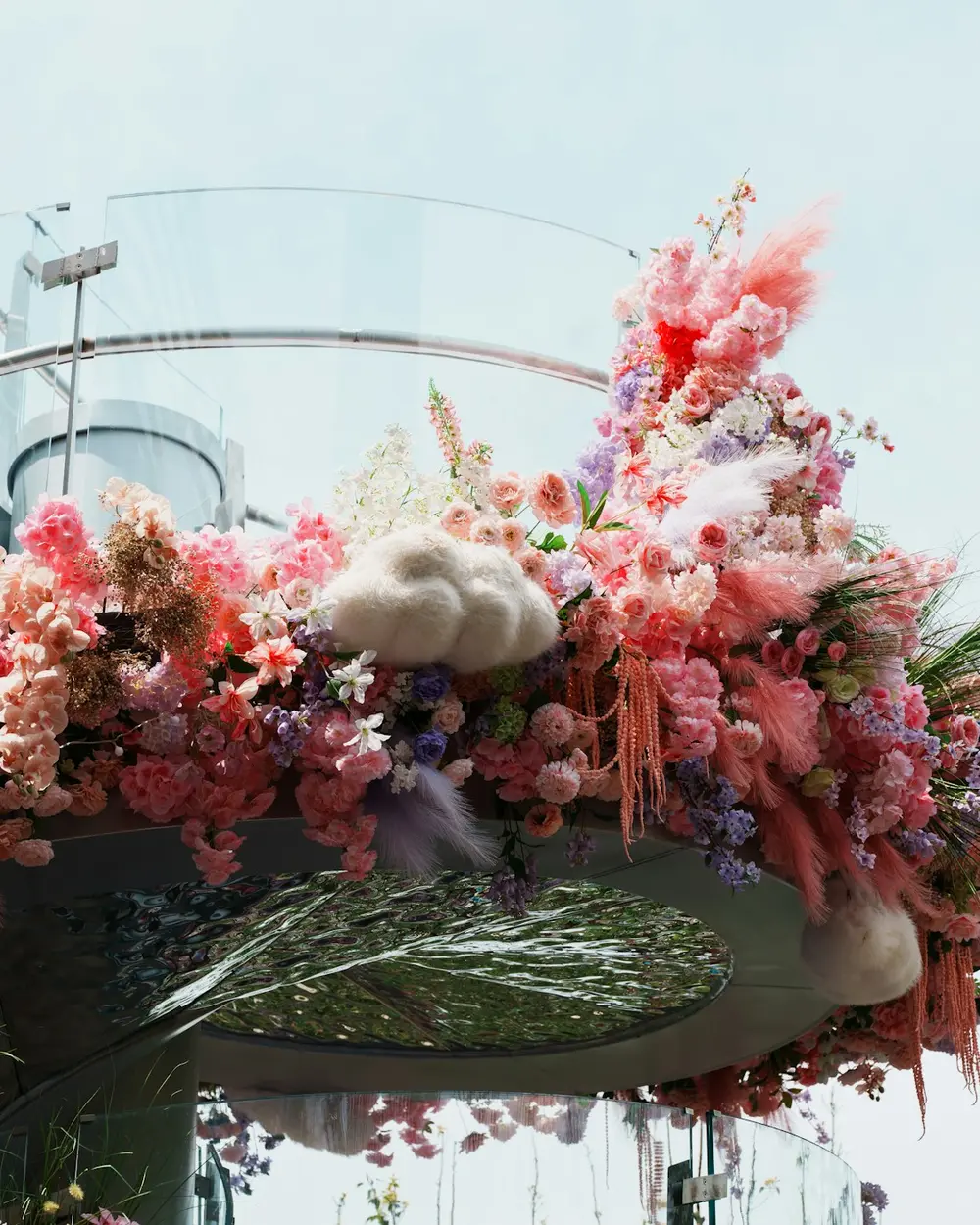 A suspended cloud of pink and coral flowers against the sky on a rooftop