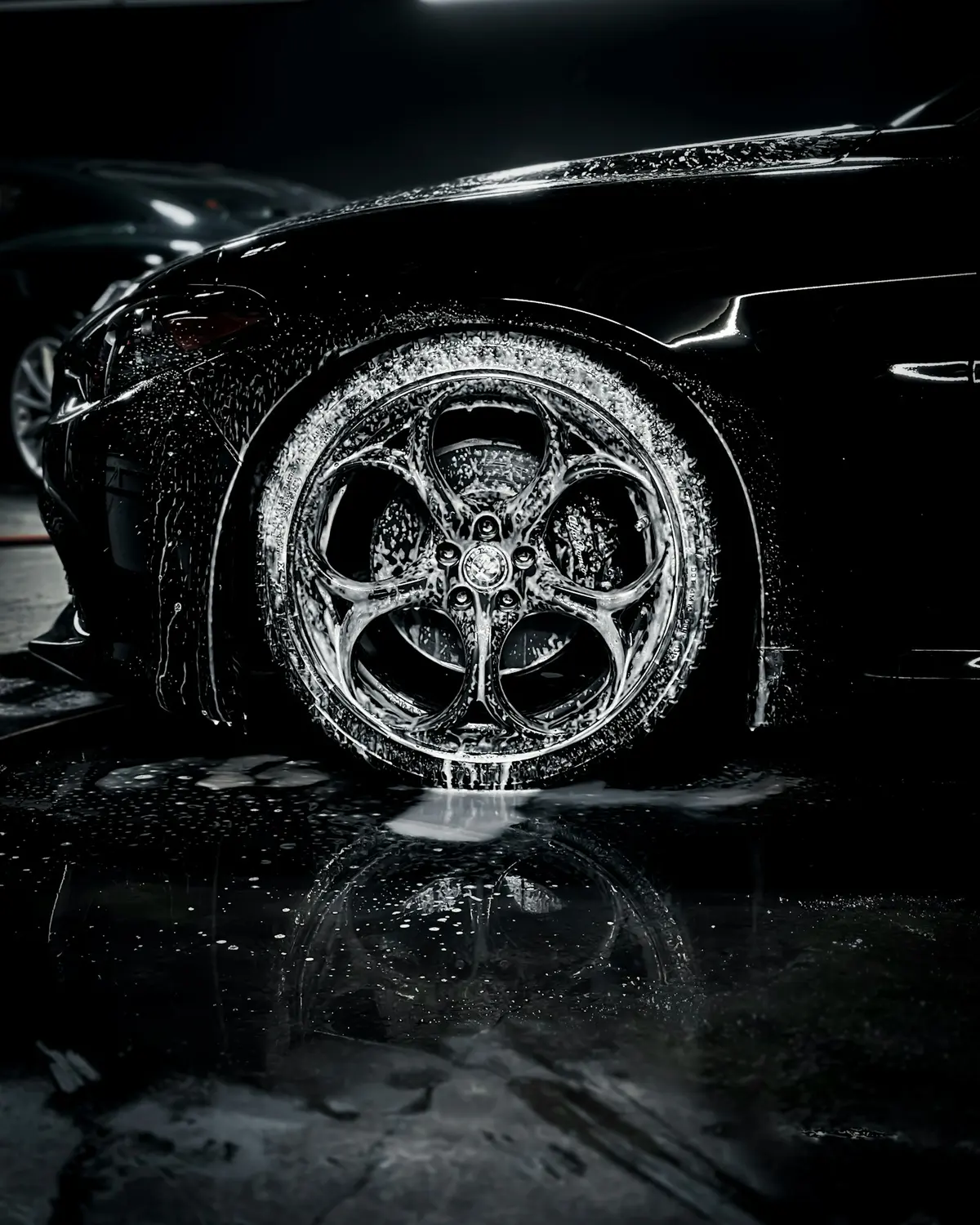 Water beading on a black wheel and tyre on a wet floor