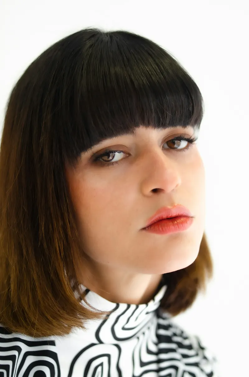 A woman with a dark blunt bob and a full straight fringe