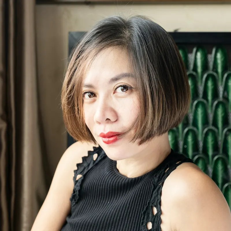 A woman with a glossy dark chin-length bob and red lipstick