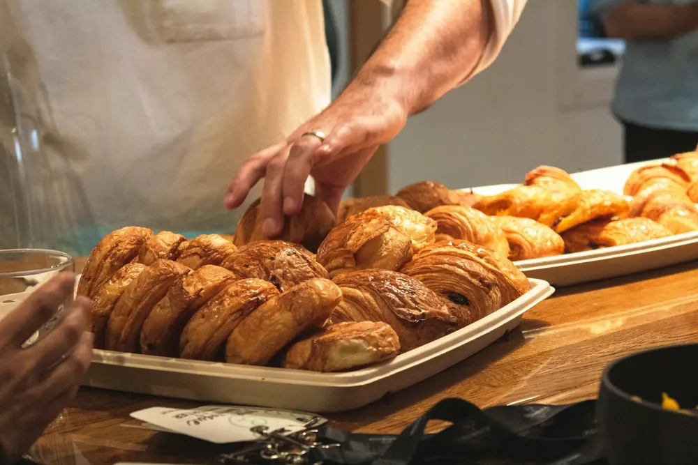 A baker's hands setting croissants out on a tray