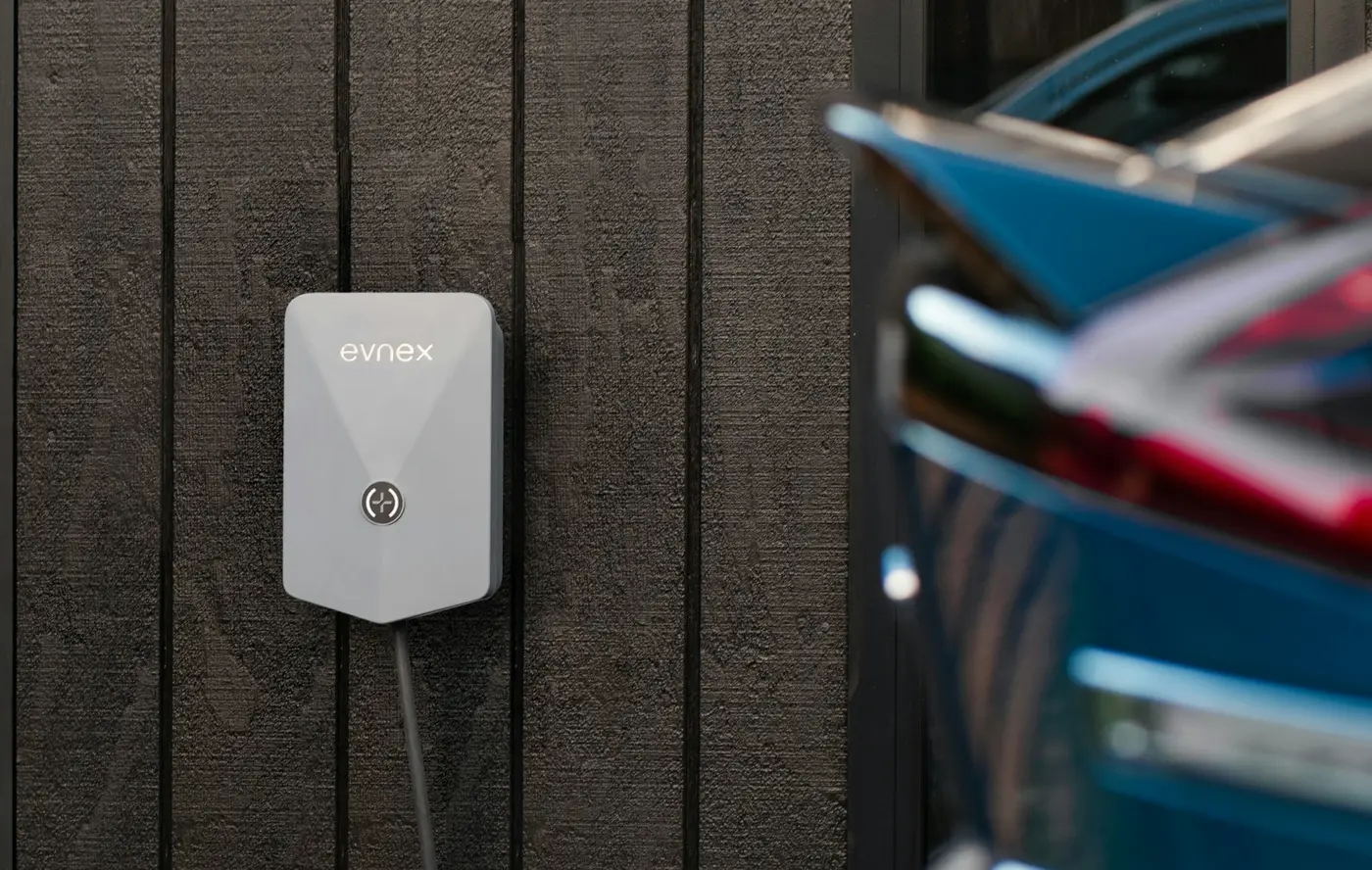 A wall-mounted home charger plugged into an electric car