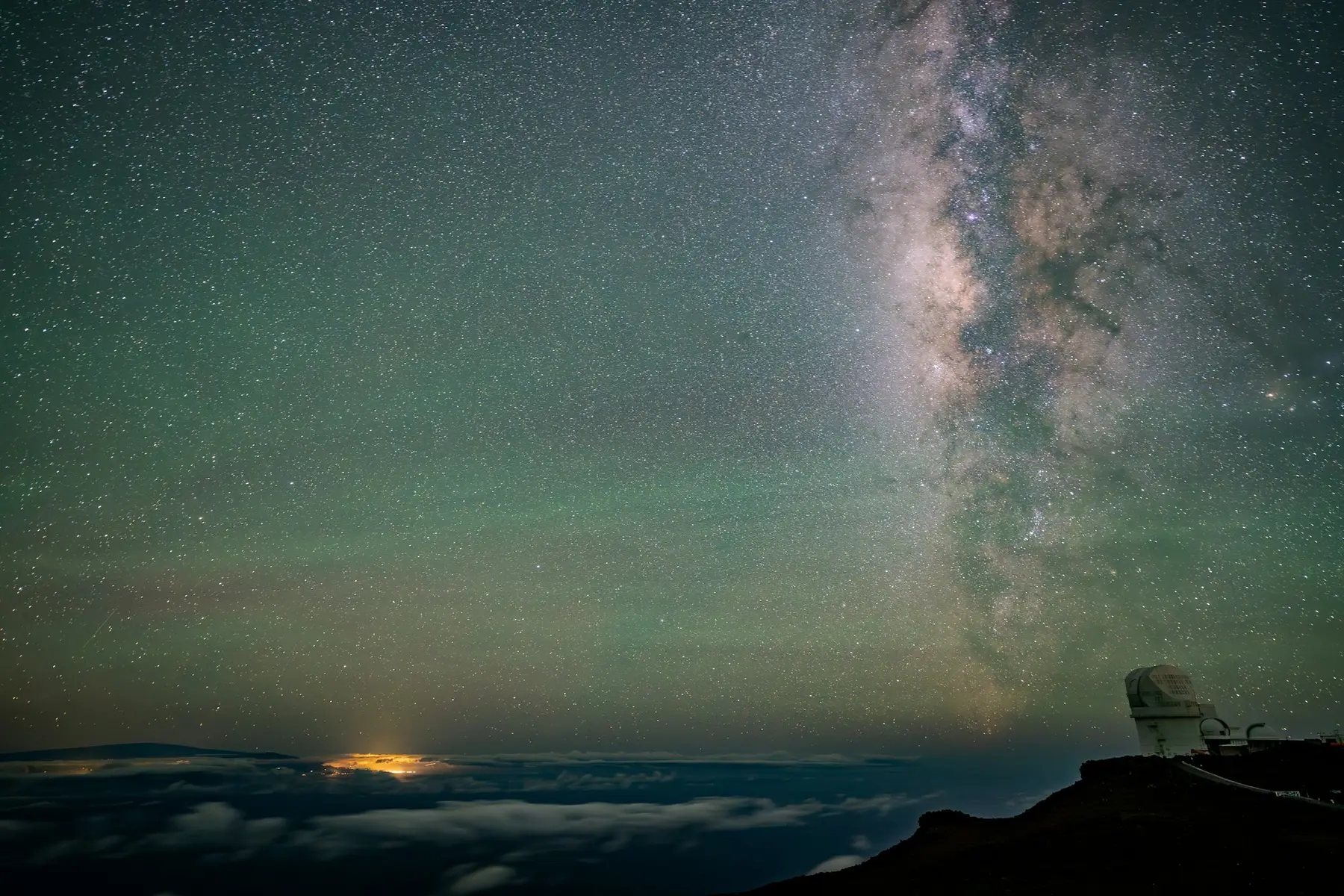 The Milky Way rising over a mountaintop observatory above a sea of cloud
