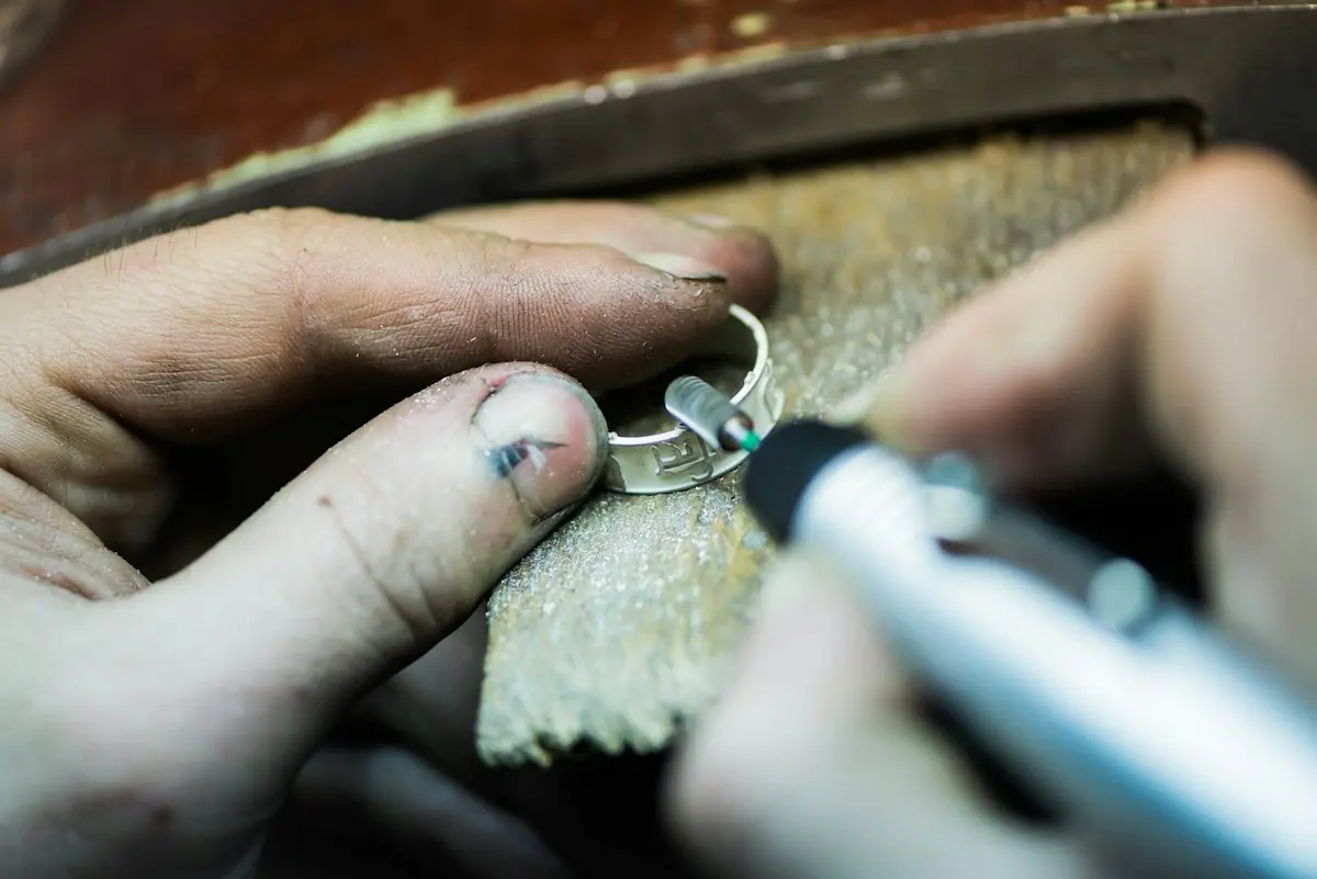 Close view of a ring being polished with a fine rotary tool against a wooden bench
