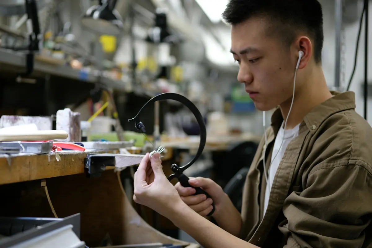 A craftsman wearing magnifying loupes working on a small piece at a cluttered bench