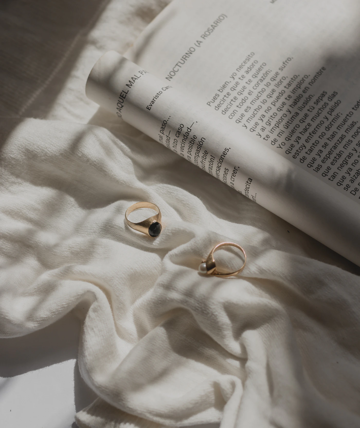 Gold rings resting on softly folded linen beside a book