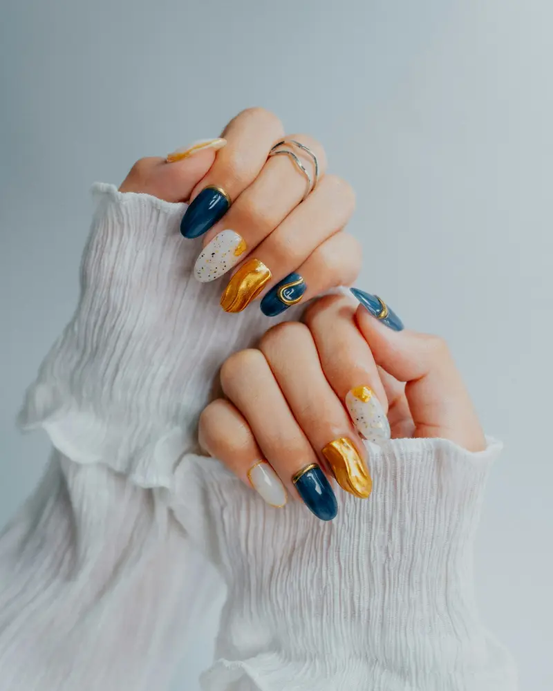Oval nails in navy, white and gold with painted scrolls and foil