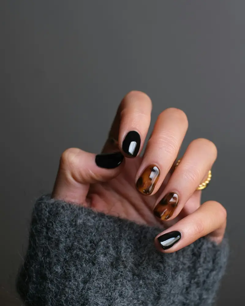 Short square nails alternating glossy black and amber tortoiseshell