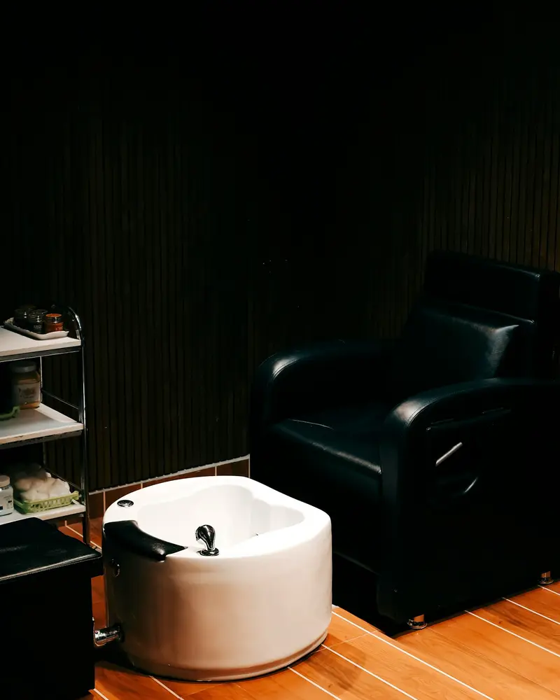 A pedicure chair with a white basin in a dim, quiet room