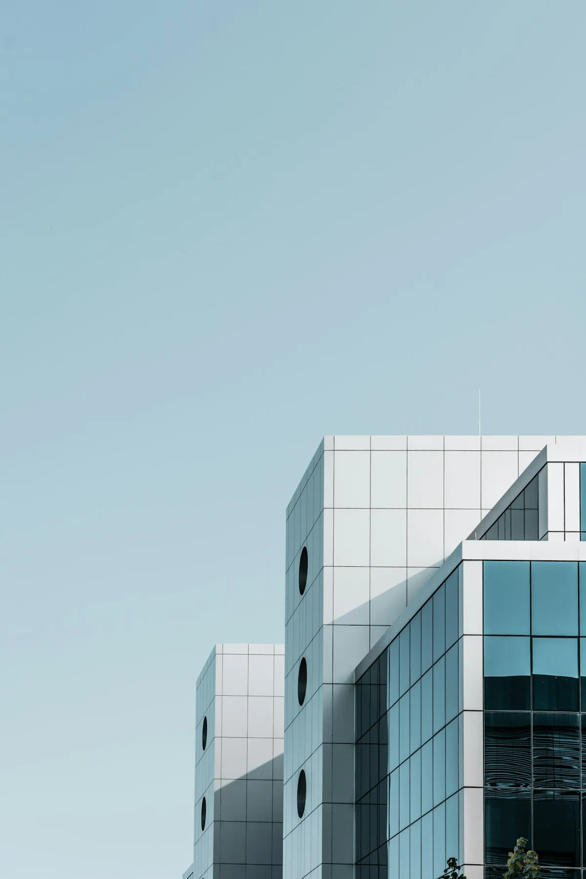 A pale concrete and glass office building against a clear sky