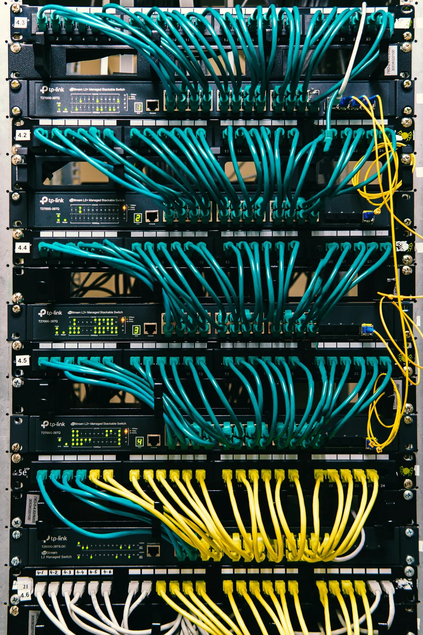 A network rack with blue and yellow patch cables dressed into patch panels