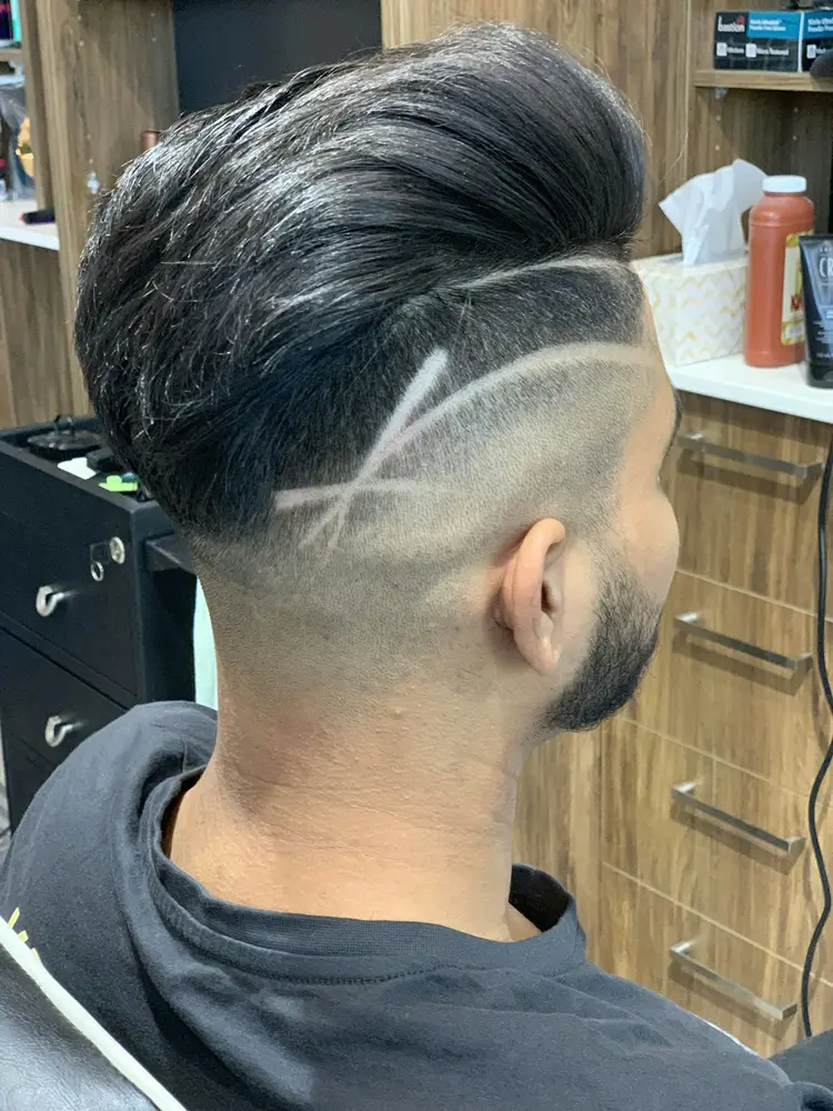 The side of a head with a low fade and a shaved part line under swept-back hair