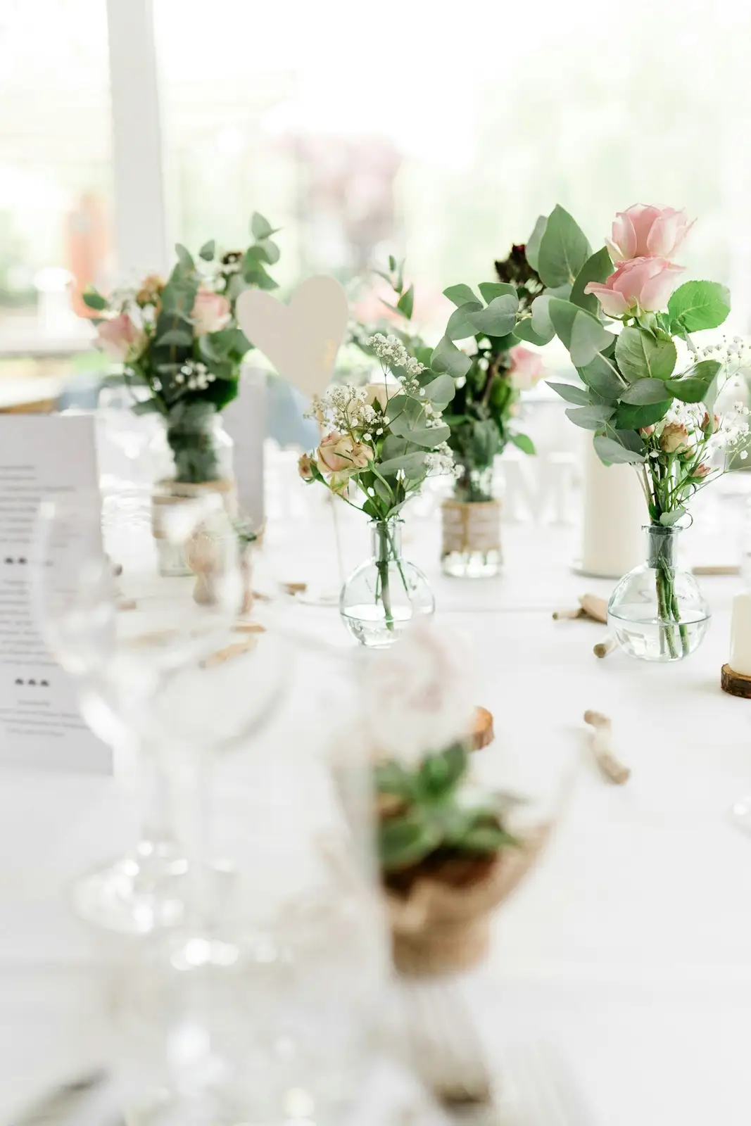 Bud vases of pink and white roses on a white table
